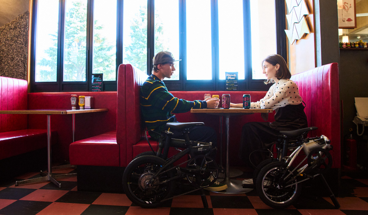 Dahon K9X folding bike parked beside two diners in a restaurant