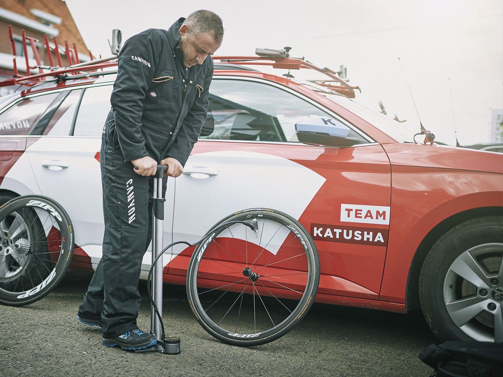 A mechanic inflating a road wheel with a floor pump, photo from the Topeak JoeBlow Ace product page